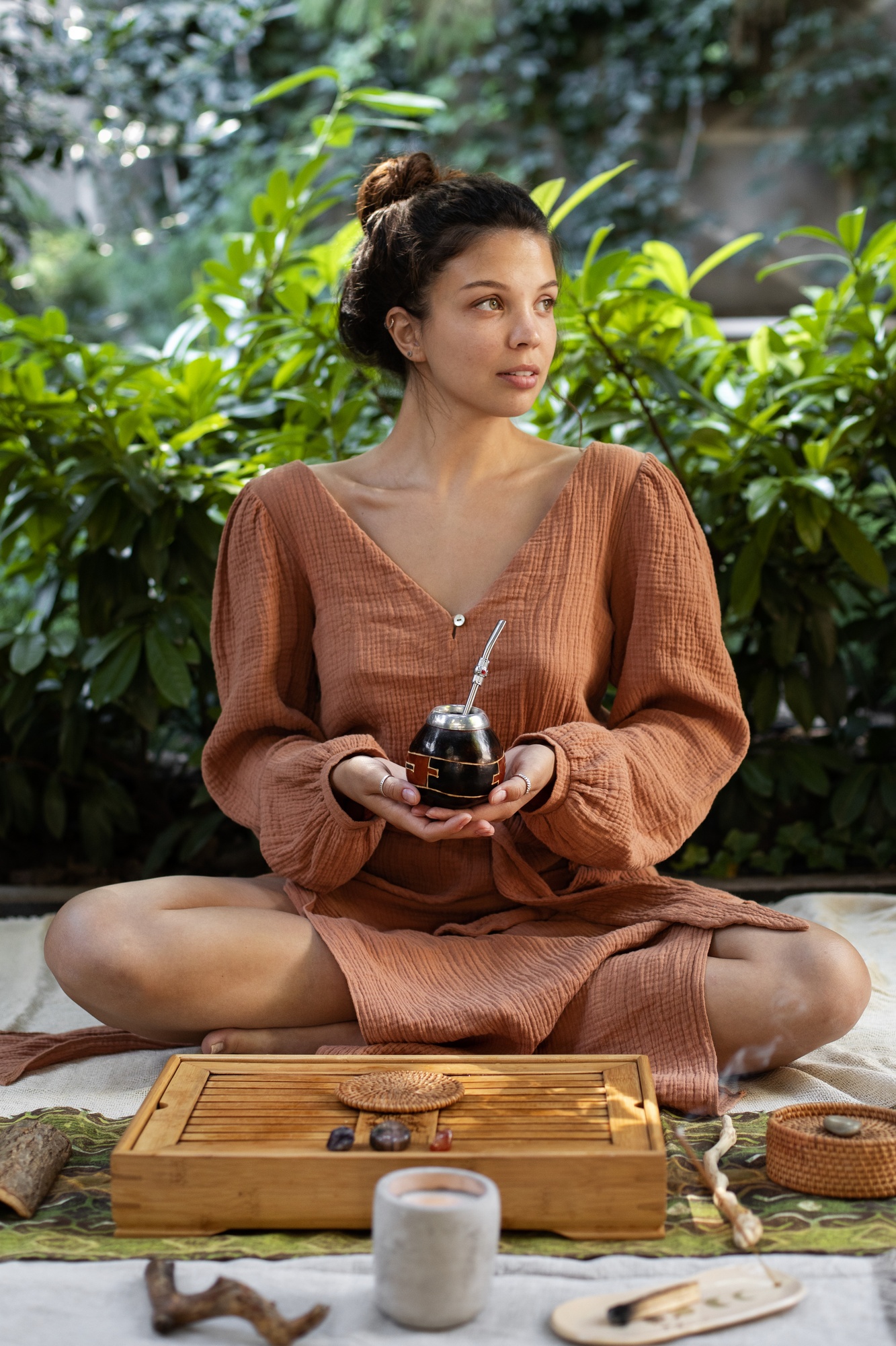 A girl lying on floor holding a jar with green plants at back 