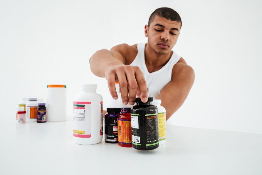 sportsman standing white wall holding vitamins mv0W0gV7oxSpryxR