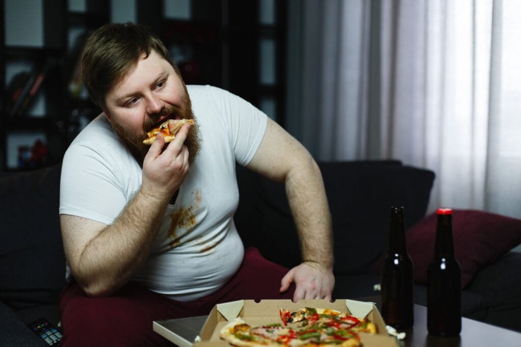 ugly fat man eats pizza sitting sofa AE0PyPKj7pIw7erO